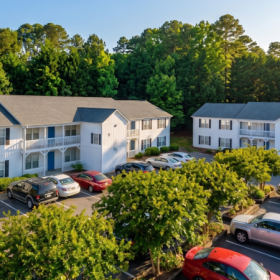 Aerial view of apartment community in Butner, NC featuring two-story buildings, tree-lined surroundings, and on-site parking in a peaceful neighborhood near major roads, shopping, and dining
